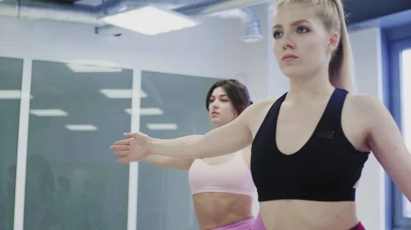 Hübsche junge Frauen machen komplexe Stretching-Yoga-Asanas im leichten Wellness-Center im Loft-Stil. — Stockfoto