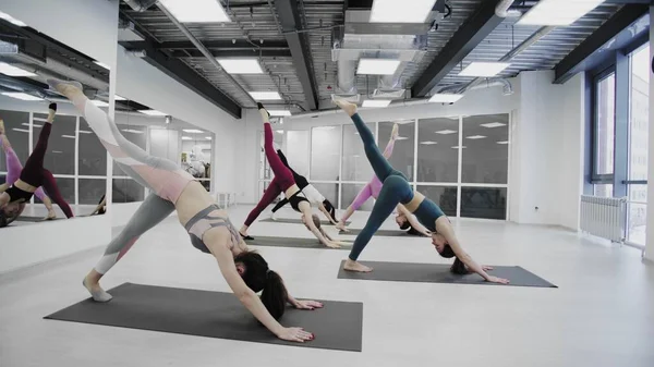 Las mujeres jóvenes están haciendo entrenamiento de yoga en un estudio moderno . —  Fotos de Stock