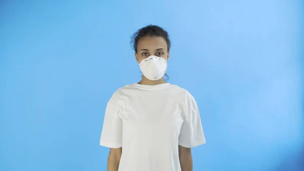 Joven afro-americana chica usando mascarilla en fondo azul —  Fotos de Stock
