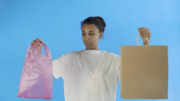 Afro-American Girl Activist trifft die Wahl zwischen Papier und Plastiktüte auf blauem Hintergrund — Stockfoto