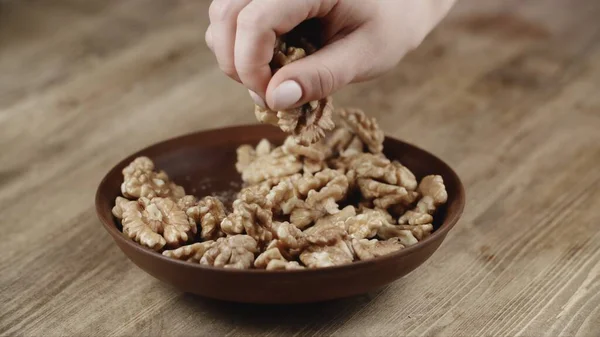 Woman Picks Up A Single walnuts, To Eat, From Her Bowl. took a nuts on the right side