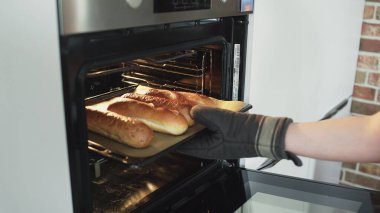 Baker sıcak ekmeği fırından çıkarır..