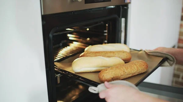 A female putting bread to the oven. — Stock Photo, Image