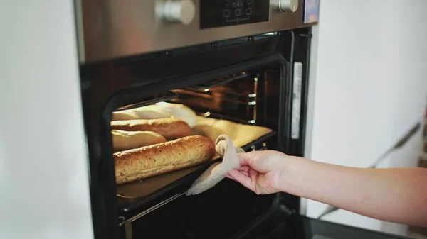 A female putting bread to the oven. — Stock Photo, Image