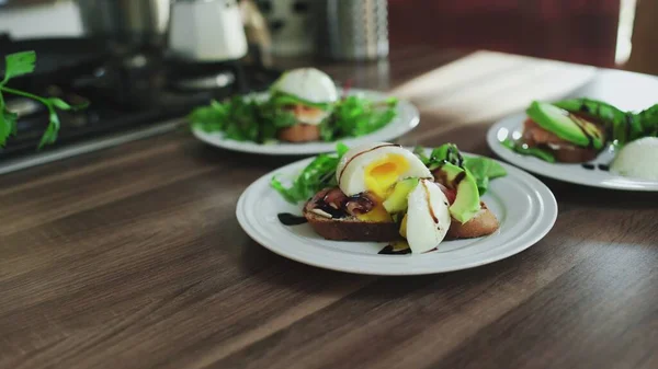 Bruschettas com salmão, abacate, queijo cottage e ovo escalfado na mesa — Fotografia de Stock