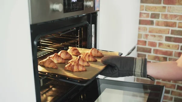 Cook taking out cooked croissants