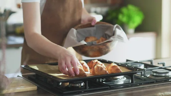 Female putting cooked croissants into wooden bowl — Stock Photo, Image