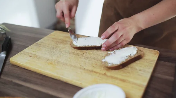 Çavdar ekmeğine peynir döken bir kadın bıçakla tost yapıyor.. — Stok fotoğraf