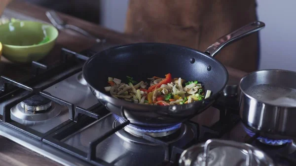 Woman frying vegetables in wok pan at home — Stock Photo, Image