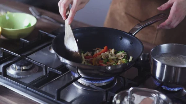 Woman frying vegetables in wok pan at home Royalty Free Stock Images