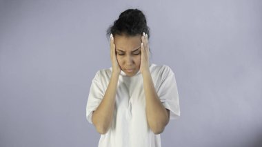 Gri arka planda korkunç baş ağrısı olan güzel genç bir kadın.