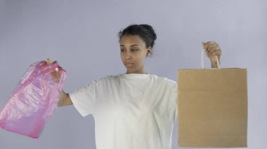 Gri arka planda kağıt ve plastik torba arasında seçim yapan Afro-Amerikalı Kız Eylemci