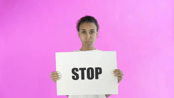 Афро-американская девушка-активистка с остановкой плакат на розовом фоне — стоковое фото
