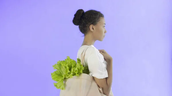 女性が野菜と袋を持っているバイオレット背景 — ストック写真