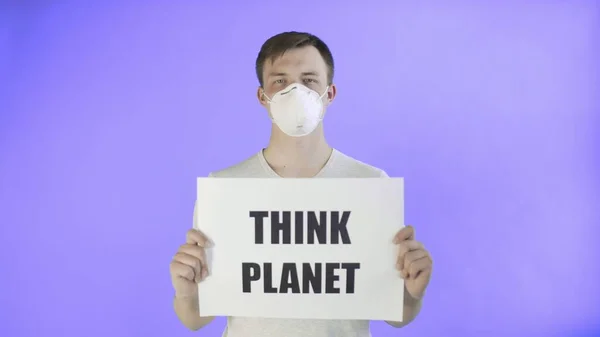 Молодой человек-активист с маской на лице и с постером "Планета" на фоне Вайолет — стоковое фото