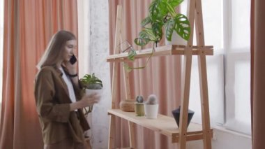 Çekici kadın telefonda konuşuyor ve kaktüse dokunuyor.