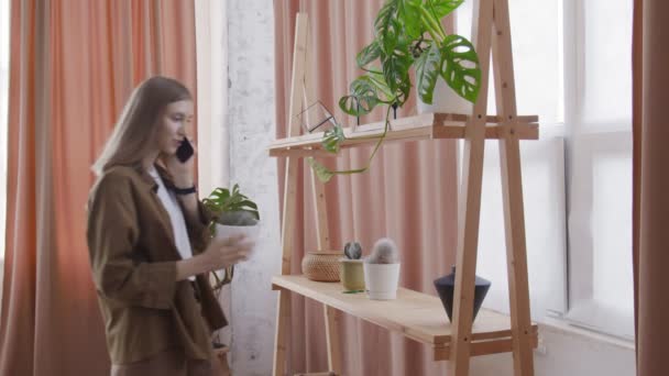 Attraktiv kvinna pratar i telefon och vidrör kaktusen — Stockvideo