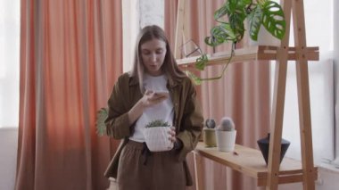 Genç yaşam tarzı blogcusu telefonda ev çiçekleri hakkında video çekiyor.