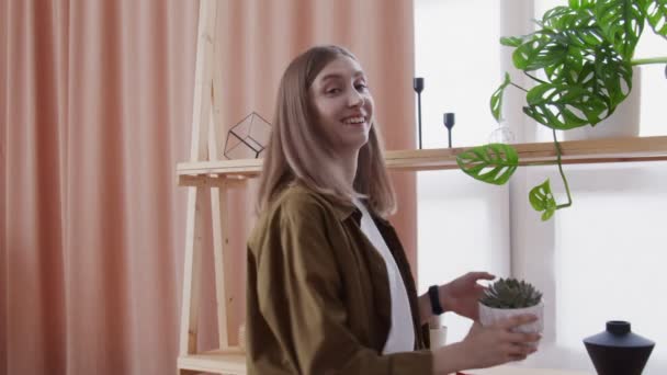 若いライフスタイルブロガーは、カメラを見て、ビデオ彼女の家の花を作る — ストック動画