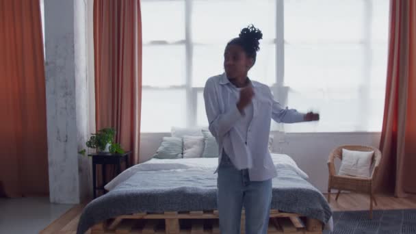 Щаслива чорна жінка танцює у спальні. Смішна африканська дівчинка-афроамериканка, яка розважається у спальні — стокове відео