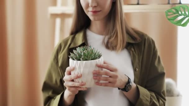 선인장을 손에 들고 미소짓고 카메라에 포즈를 취하는 젊은 여성 정원사. — 비디오