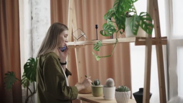 Atraktivní žena mluví po telefonu a zkontrolujte její kaktus — Stock video