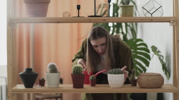 Mladá žena drží červené zalévání může vody dům rostliny v květináčích — Stock video