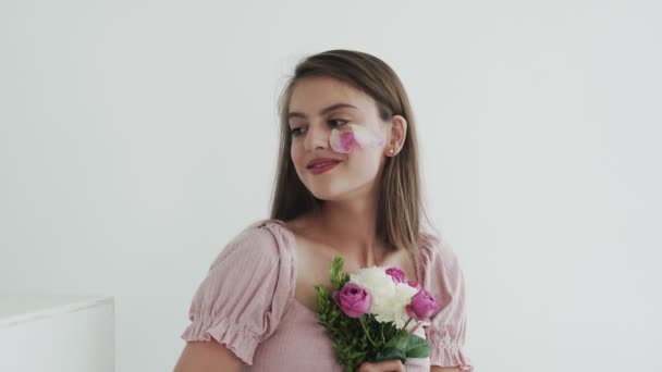 Modelo jovem bonita atraente com flores olhando e posando para a câmera — Vídeo de Stock