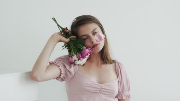 Aantrekkelijke mooie jonge vrouw model met bloemen op zoek en poseren op camera — Stockvideo