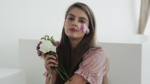 Modelo jovem bonita atraente com flores olhando e posando para a câmera — Vídeo de Stock