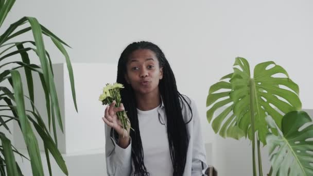 Atractiva hermosa mujer afroamericana modelo con flores mirando y posando en la cámara — Vídeo de stock