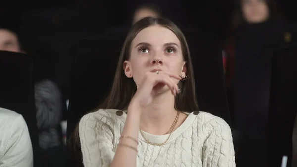 Close up of a scared young woman using her hands to cover her face while watching a scary movie. — Stock Photo, Image