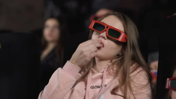 Mujer joven con gafas 3d está viendo películas y comiendo palomitas de maíz en el cine — Foto de Stock