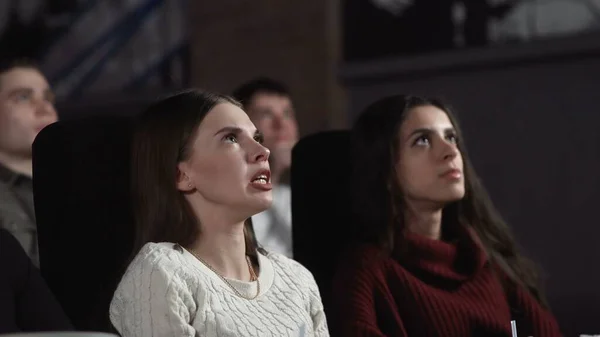 Close up of two pretty female friends are eating popcorn and watching a movie in the cinema — Stock Photo, Image