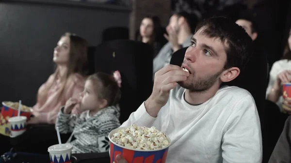 Dolly move de pessoas estão comendo pipocas e assistindo a um filme no cinema — Fotografia de Stock