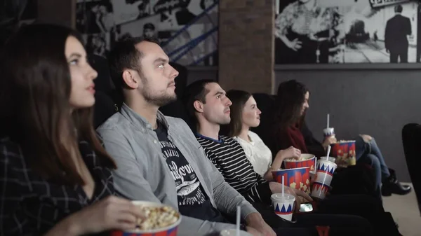 Amigos felices viendo películas en el teatro. Pareja y otras personas comiendo palomitas de maíz y bebiendo refrescos mientras ven películas en el cine . — Foto de Stock