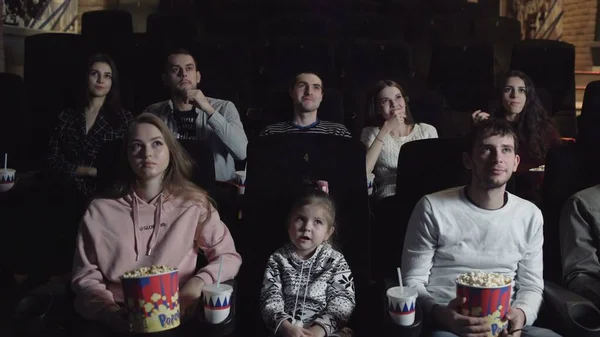 Jeunes assis au cinéma, regardant un film et mangeant du pop-corn, concept d'amitié et de divertissement — Photo
