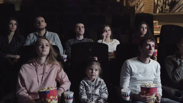 Jóvenes sentados en el cine, viendo una película y comiendo palomitas de maíz, concepto de amistad y entretenimiento — Foto de Stock