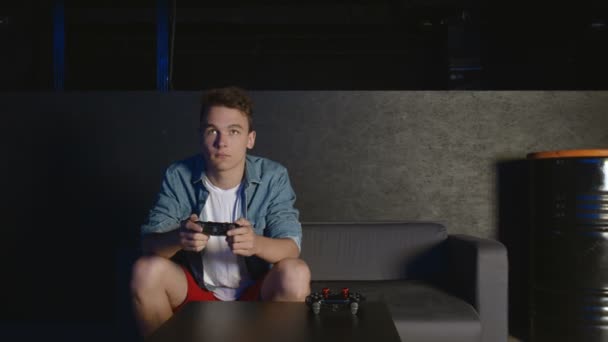 Δύο νεαροί φίλοι που παίζουν βιντεοπαιχνίδι δράσης στο σαλόνι καθισμένοι στον καναπέ — Αρχείο Βίντεο