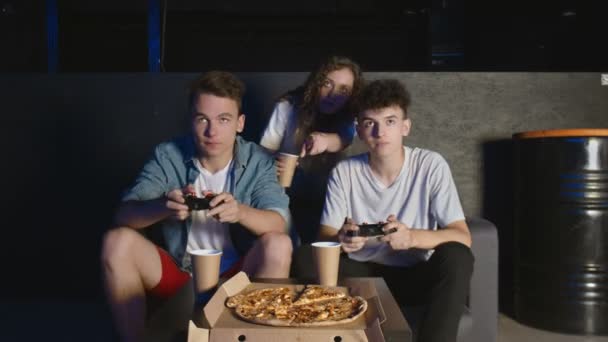 年轻快乐的朋友们在家里的聚会上玩电子游戏.他们在电视屏幕上指指点点 — 图库视频影像