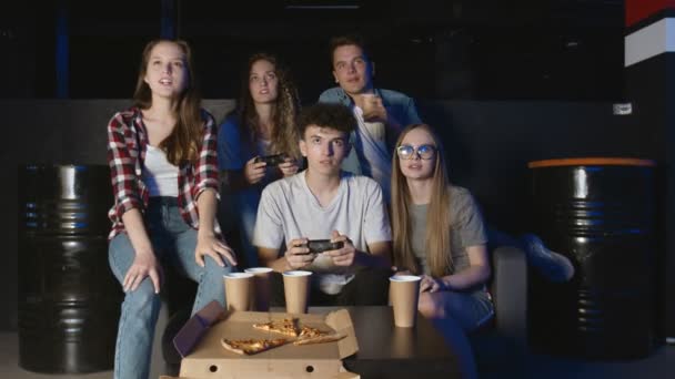 Grande compagnie d'amis se détendre sur le canapé du salon et jouer à des jeux vidéo. S'amuser avec des amis. — Video