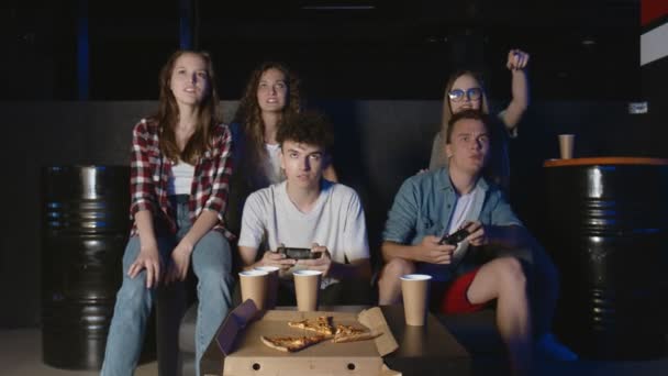 Młodzi przyjaciele bawią się w domu grą wideo, jeden chłopak wygrywa śmiech, a drugi przybija piątkę, drugi jest zdenerwowany.. — Wideo stockowe