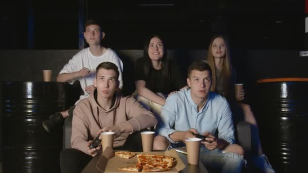 Grande companhia de amigos relaxando no sofá da sala de estar e jogando videogames . — Vídeo de Stock