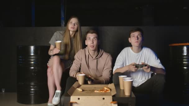 Счастливая компания друзей наслаждается отдыхом, играя в видеоигры и получая удовольствие — стоковое видео
