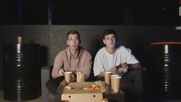 两个男性朋友在电子游戏中获胜，坐在沙发上，青少年友谊 — 图库视频影像