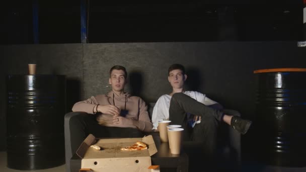 两个最好的朋友一起在沙发上看电视，交流，吃爆米花和披萨 — 图库视频影像