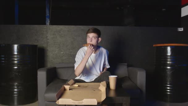 若いです男食べるピザと見てテレビホームリラックスオンソファ — ストック動画