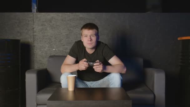 Junger Mann spielt Konsolenspiel vor der Kamera und schlägt seinen Gegner online. Weißer Mann auf dem Sofa. — Stockvideo