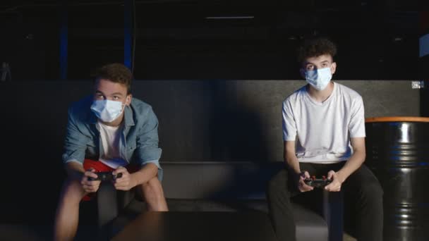 Two gamers with face masks in front of the screen are playing together in the online battle — Stock Video