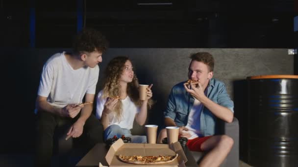 Jonge vrienden eten pizza en praten in de donkere kamer — Stockvideo